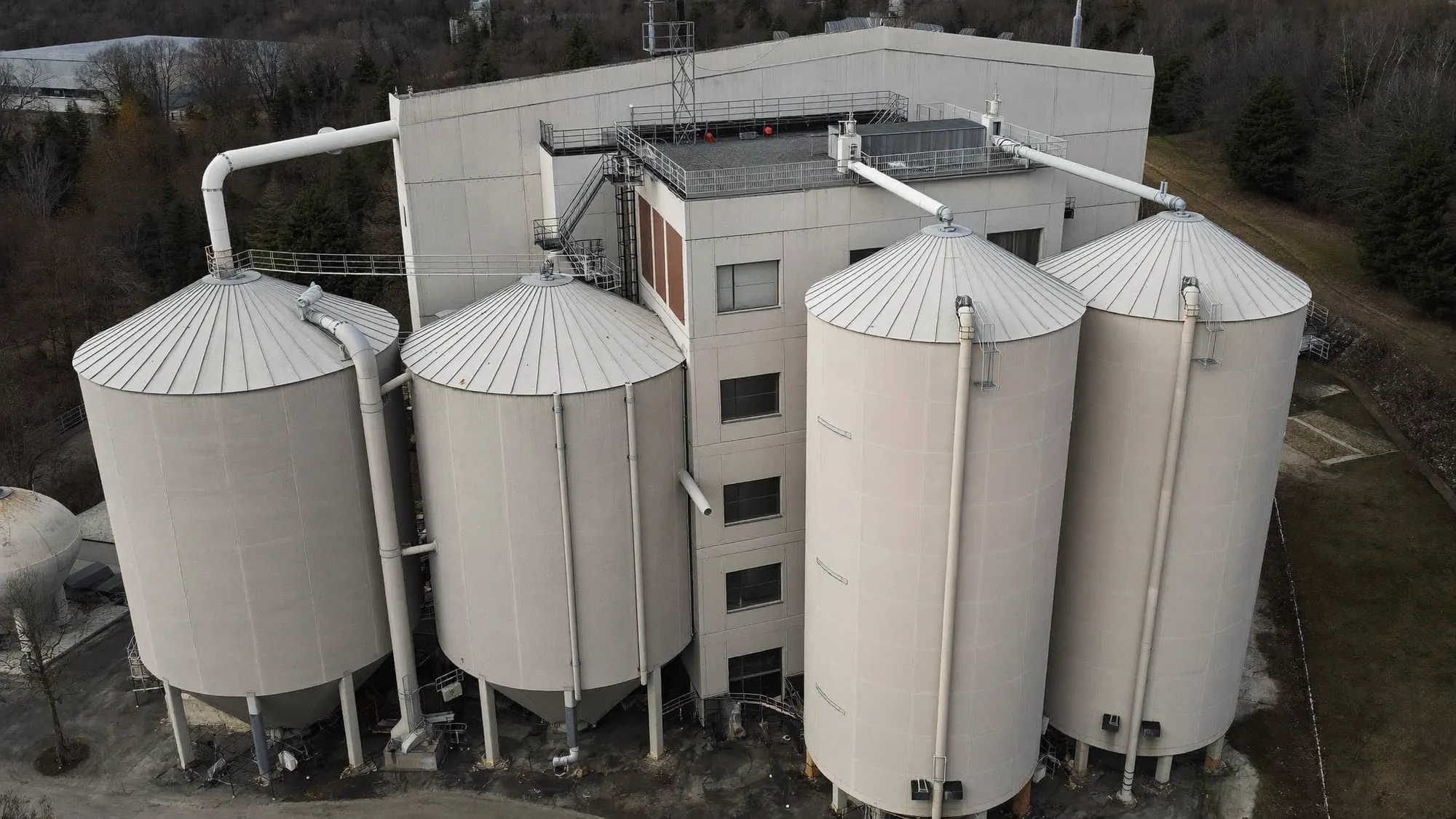 Silos e prédio de produção de cervejaria com fachada pintada em cinza claro (imagem ilustrativa).